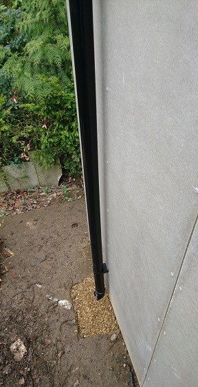 Garden room's black PVC guttering and a downpipe connected to a local soakaway